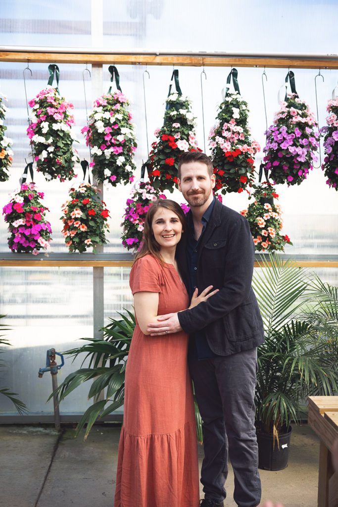 mother and husband in front of flowers at green house for family portraits with juniper lynne photography in port orchard washington