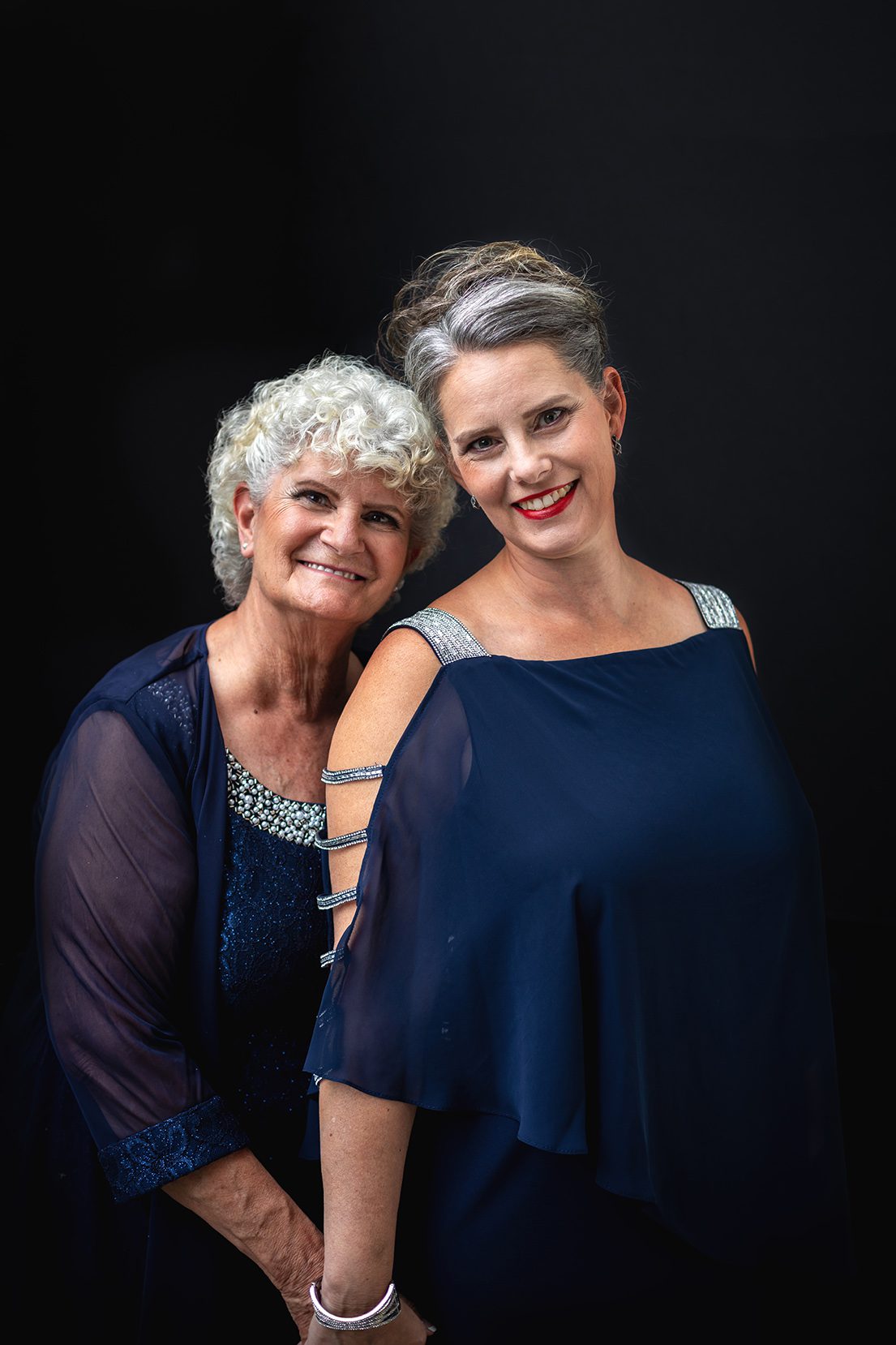 Over 50 mother and daughter studio portrait wearing blue dress with grey hair by Juniper Lynne Photography in Port Orchard Washington