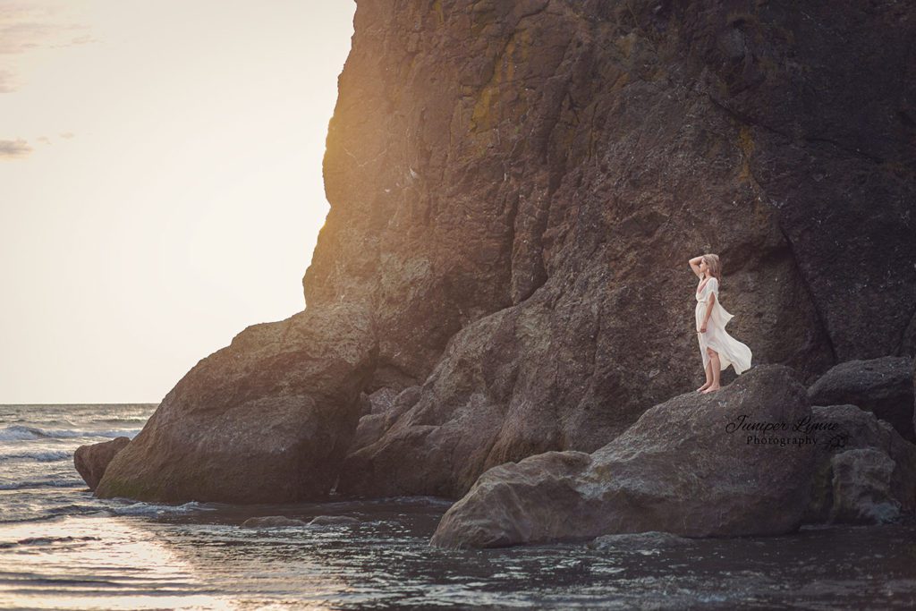 Romantic and adventurous woman on rock at Ruby Beach Washington for Destination photo session with Juniper Lynne Photography of Gig Harbor