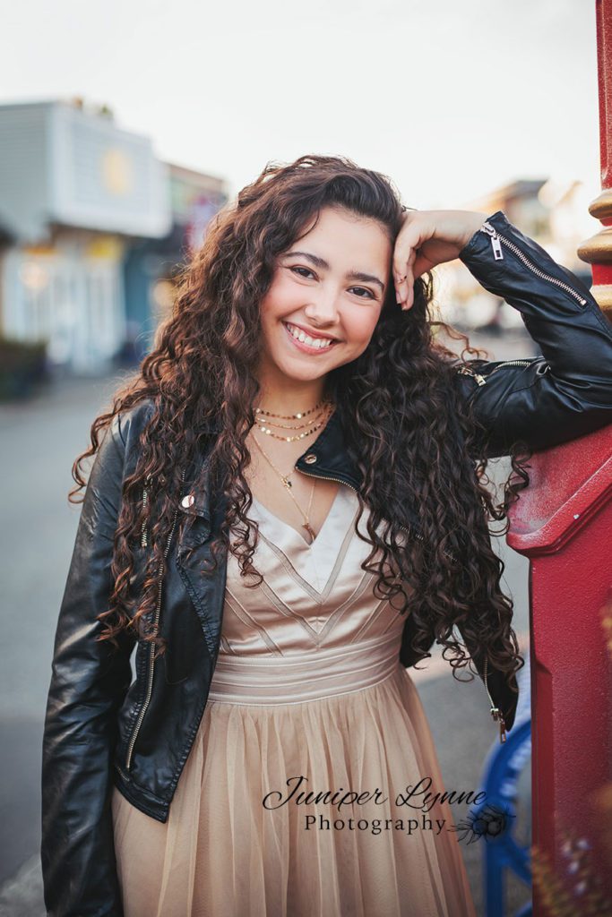 High school senior girl in rose gold homecoming dress and leather bomber jacket in downtown Poulsbo Washington what to wear with Juniper Lynne Photography in Gig Harbor