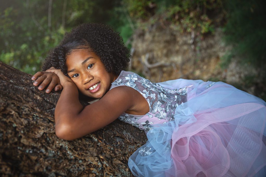 Black girl in purple couture princess ball gown laying in tree in Gig Harbor Washington for Juniper Lynne Photography