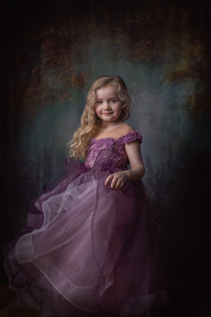 Little girl in purple couture princess dress gown in studio setting with painterly background for Juniper Lynne Photography in Port Orchard Washington