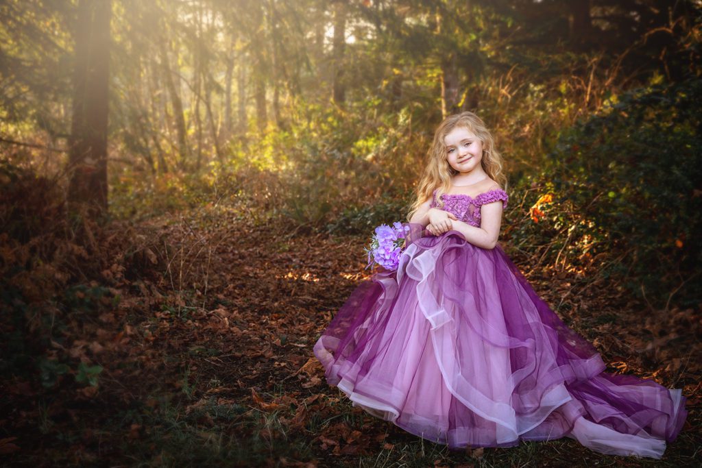 5 year old blond girl in purple couture princess dress outside in forest in Port Orchard Washington by Juniper Lynne Photography